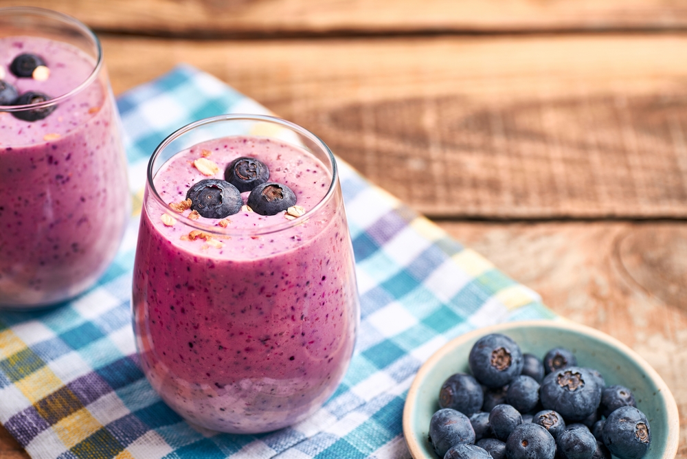 Blueberry smoothie in glass. Homemade blueberry smoothie on rustic wooden table. Blueberry smoothie with yogurt and oats.