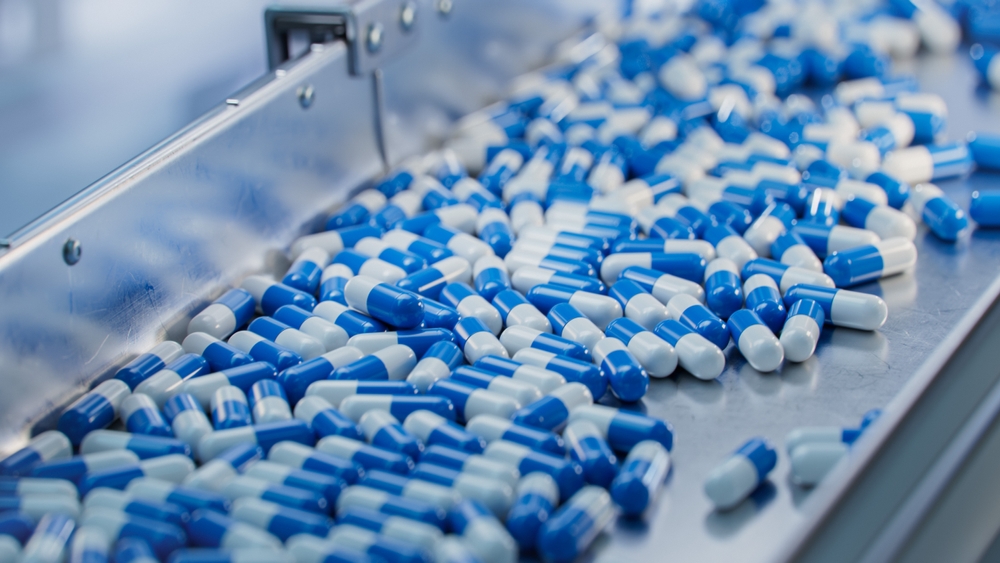 Blue Capsules are Moving on Conveyor at Modern Pharmaceutical Factory. Tablet and Capsule Manufacturing Process. Close-up Shot of Medical Drug Production Line.
