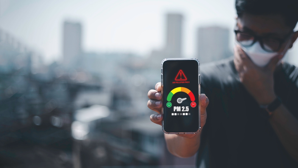 man scanning the weather on his mobile phone Ecological concept. Allergies. Headache.N95 PM 2.5 from air pollution and dust beyond safety standards. health care, environment,