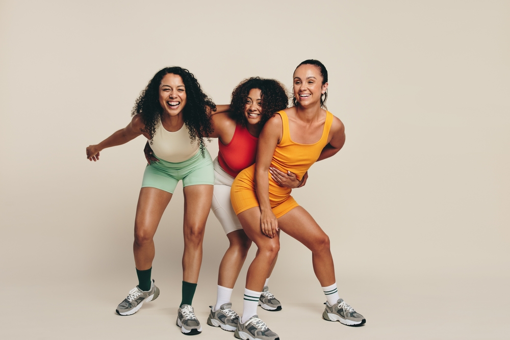 Group of young female athletes laughing and having fun in fitness clothing, celebrating their love for sport and exercise. Happy young sportswomen demonstrating their commitment to a healthy lifestyle