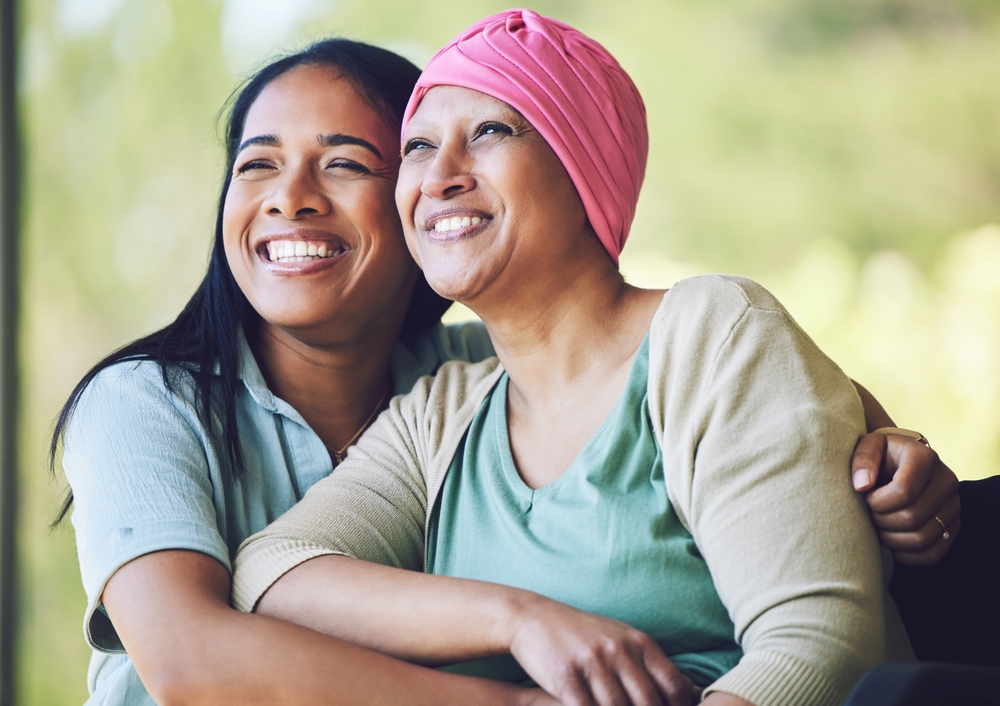Love, bonding and woman with her mom with cancer hugging, sitting and spending time together. Happy, sweet and sick mature female person embracing her adult daughter with a smile in outdoor garden.