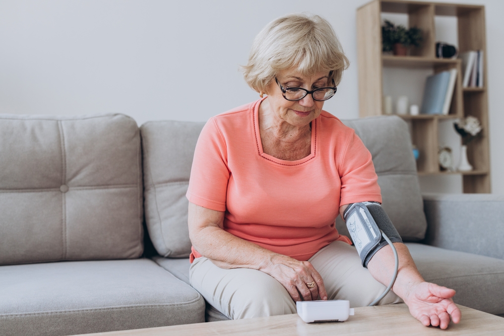 Senior woman with hypertension measuring blood pressure herself at home. Sad Mature lady measure blood pressure using tonometer. Everyday health check-up