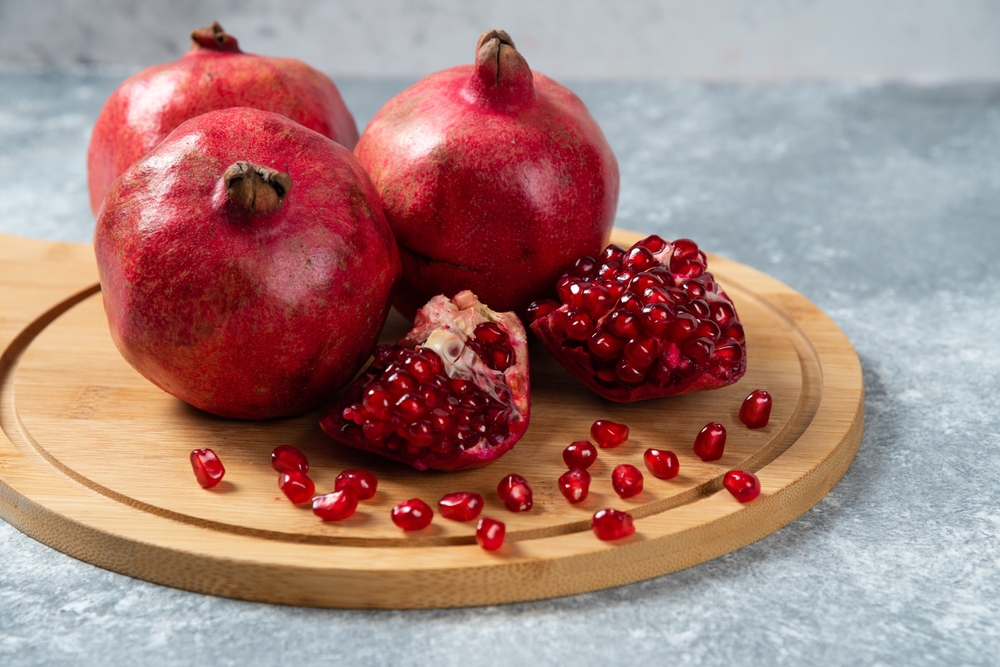 Several ripe pomegranate fruits and an open pomegranate, pomegranate on table, top view, dark background, Fresh ripe pomegranate on black background, selective focus, Healthy pomegranates fruit garn