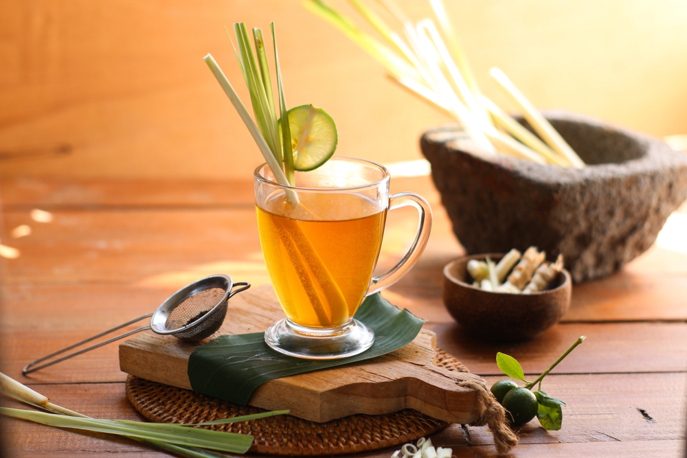 Cup of hot lemongrass tea with sliced and green leaf on brown wooden background. Lemongrass for healthy herbal drink concept