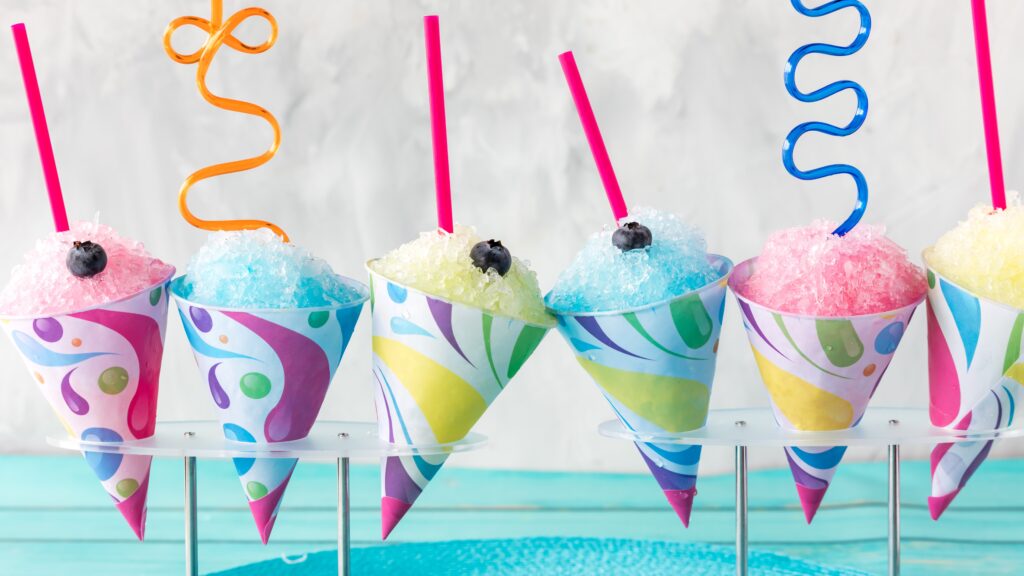 A row of flavoured snow cones with silly straws against a light background.