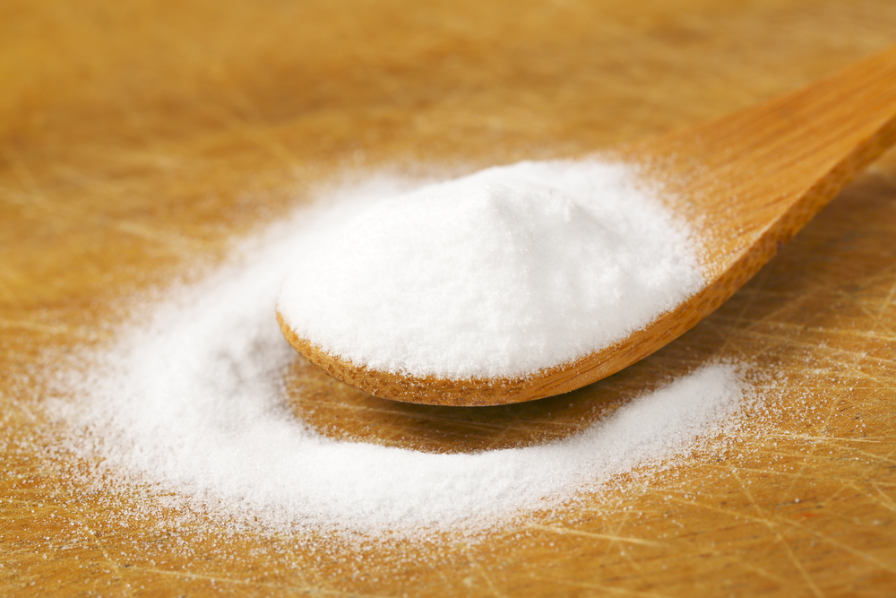 spoon of cooking soda on wooden cutting board