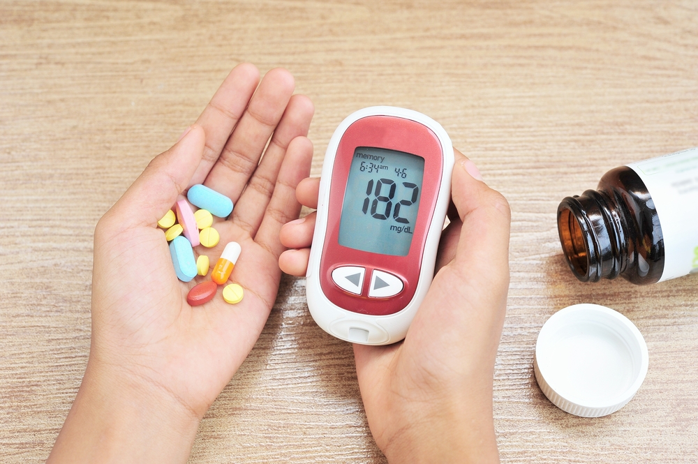 Hands hold glucometer and medicine.