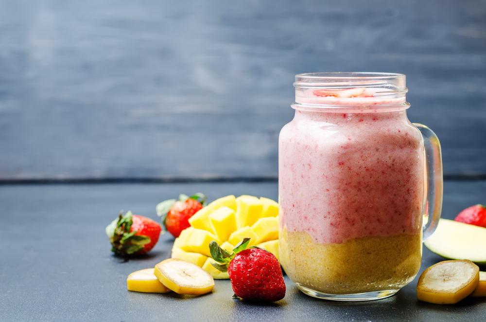 Mango strawberry banana smoothie on a black background. toning. selective Focus