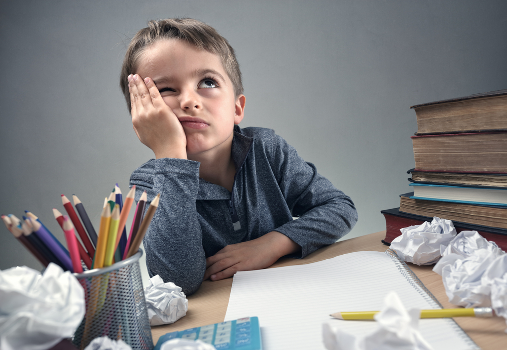 Thinking child bored, frustrated and fed up doing his homework

