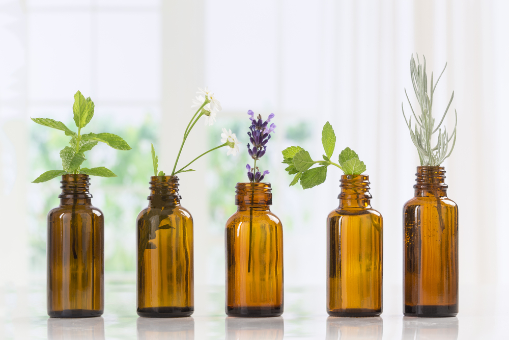 Brown Bottles of essential oil with fresh herbs