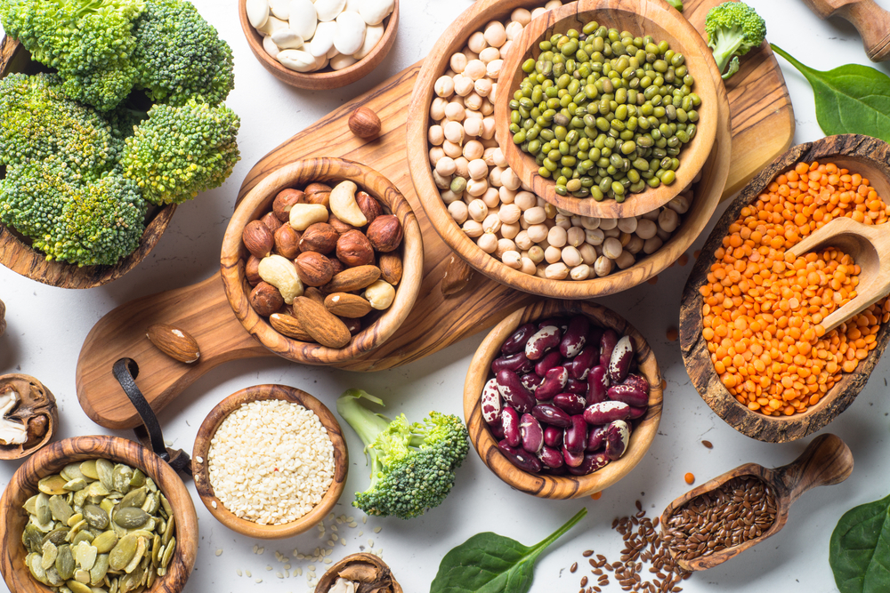 Vegan protein source. Beans, lentils, nuts, broccoli spinach and seeds. Top view on white table. Healthy vegetarian food.

