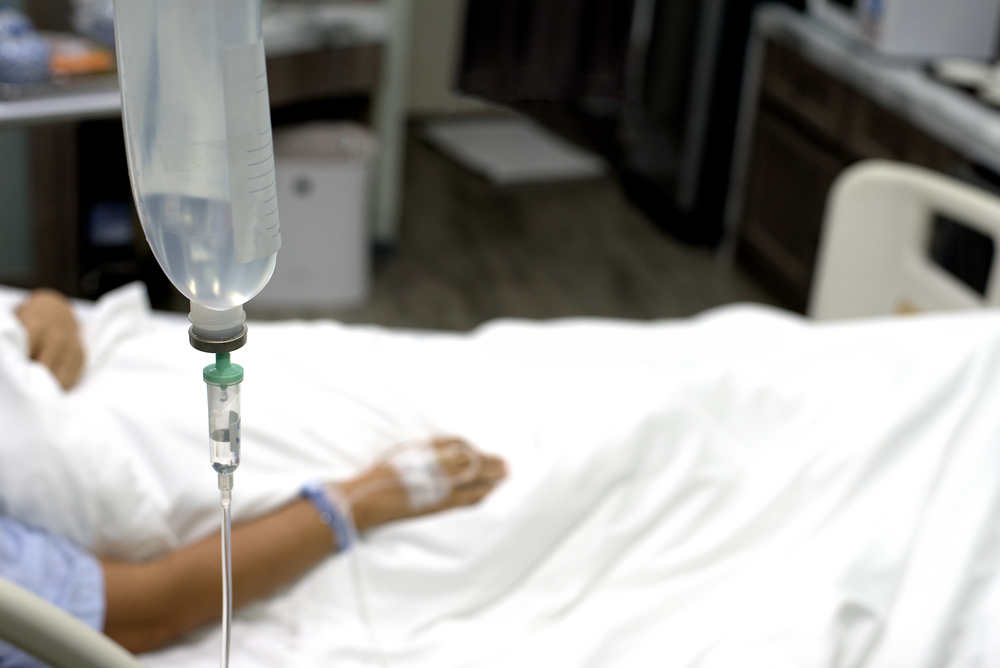 Patient laying on patient's bed in hospital, patient receive saline solution to treat illness.