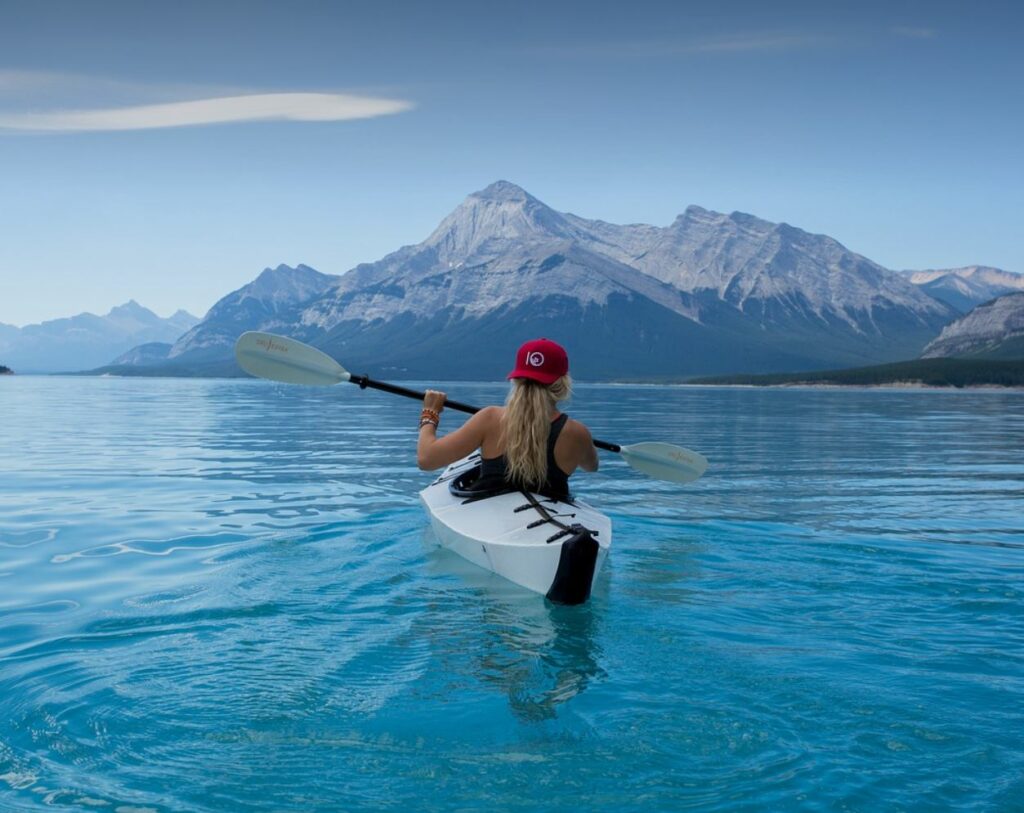 Woman kayaking. Mountain and water in the background.