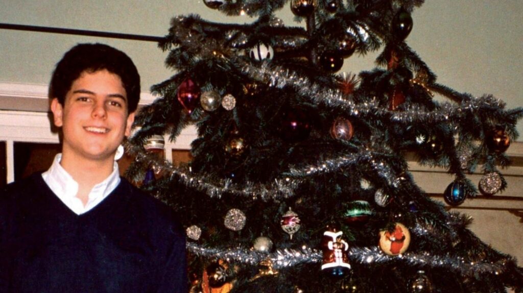 Carlo posing beside a Christmas tree.