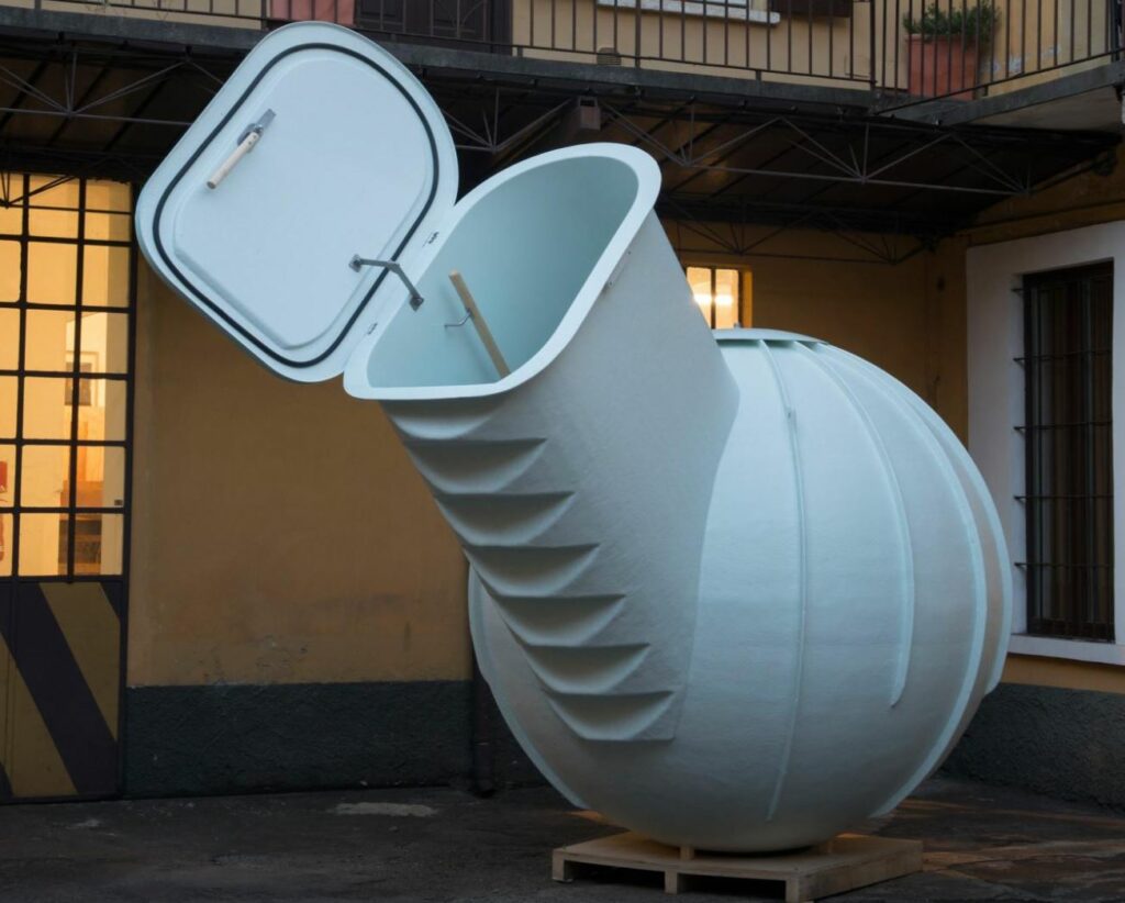 A picture of the ground fridge. Widows, walls, rails, and a plant in the background.