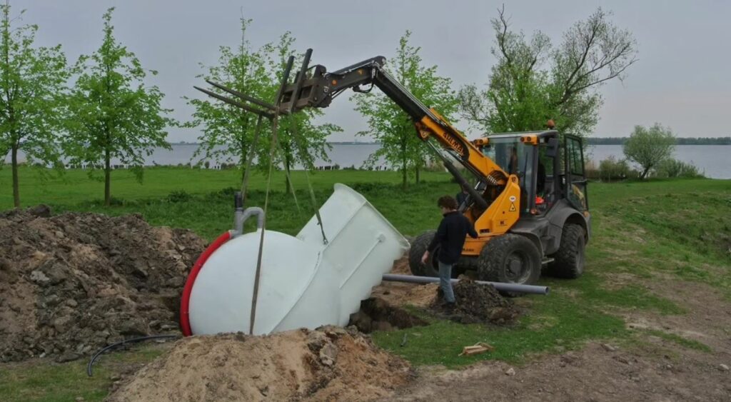 A tractor dropping the fridge into its place. Trees and grass in the background.
