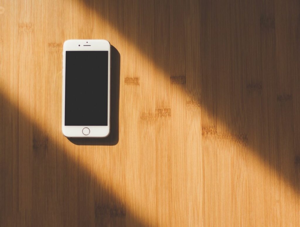 I phone with light colored wood in the background. 