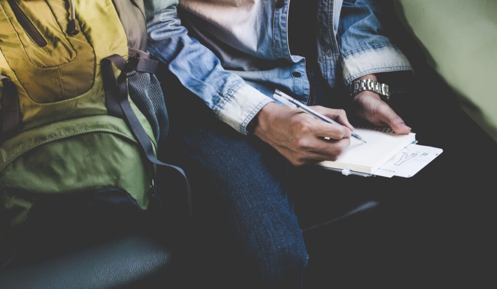 man travelling taking notes while holding his boarding pass 