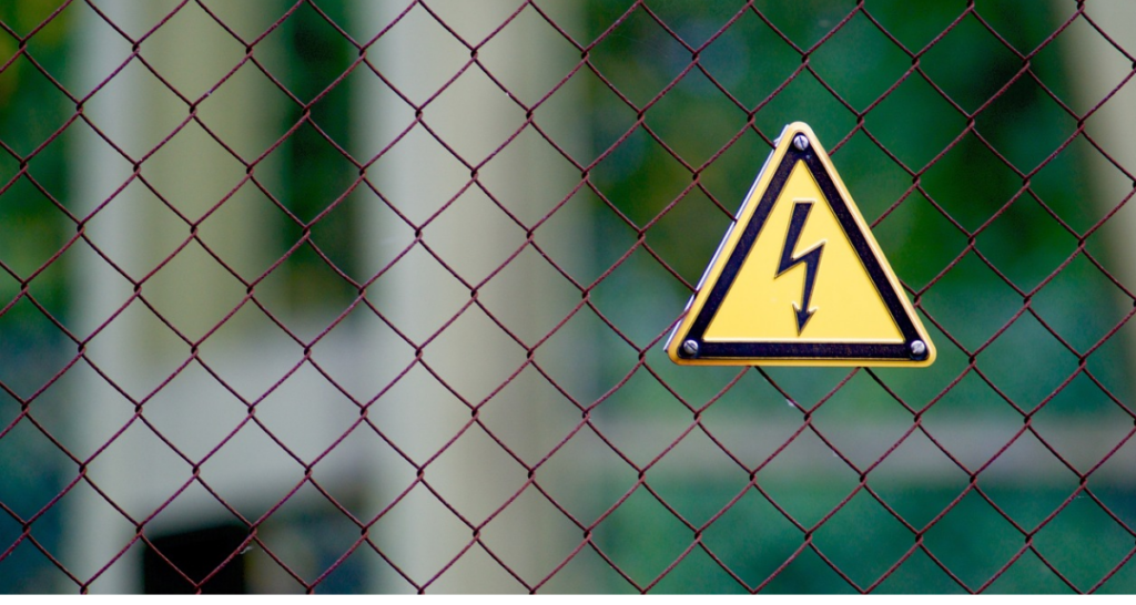 Electrical warning sign on a fence. Blurred background.