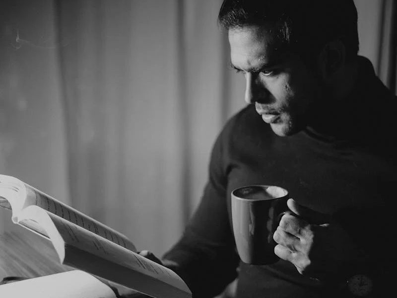 Man reading and drinking coffee at night