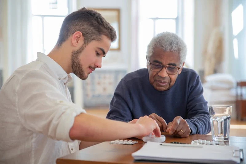 young man helping older man with pills