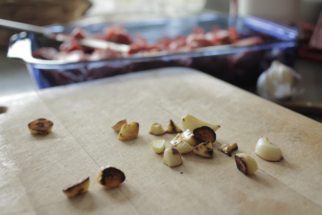 A cutting board with chopped up burnt garlic 
