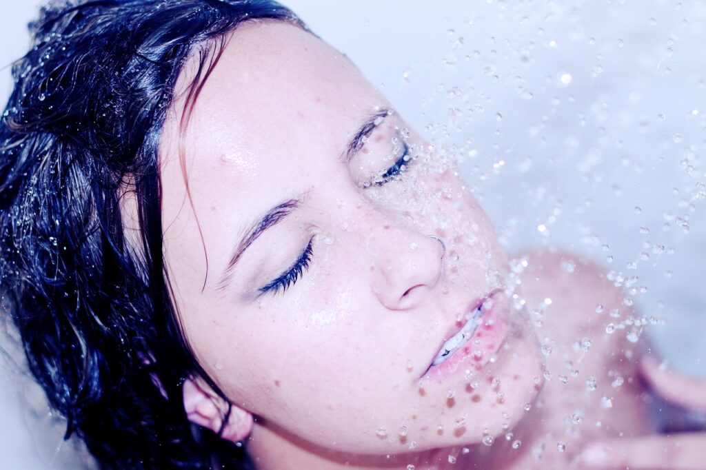 Close up of a dark-haired woman taking a shower.