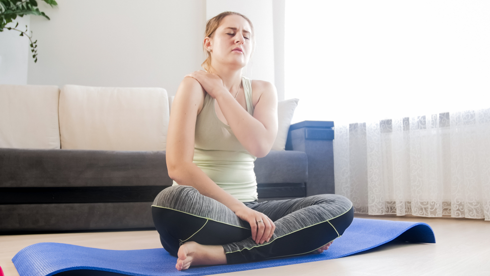 Woman feeling pain in shoulder after exercising at home
