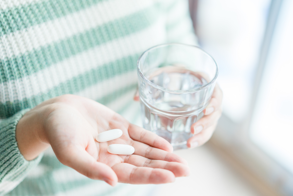 Close Up Of Girl holding Pill and glass of water.With Paracetamol.Nutritional Supplements.Sport,Diet Concept.Capsules Vitamin And Dietary Supplements.