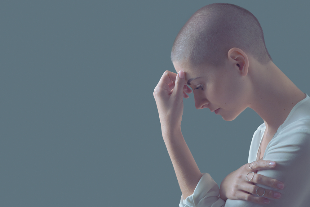 Sad, frightened and depressed female cancer patient portrait with copy space. Breast cancer patient, head in hands, portrait.