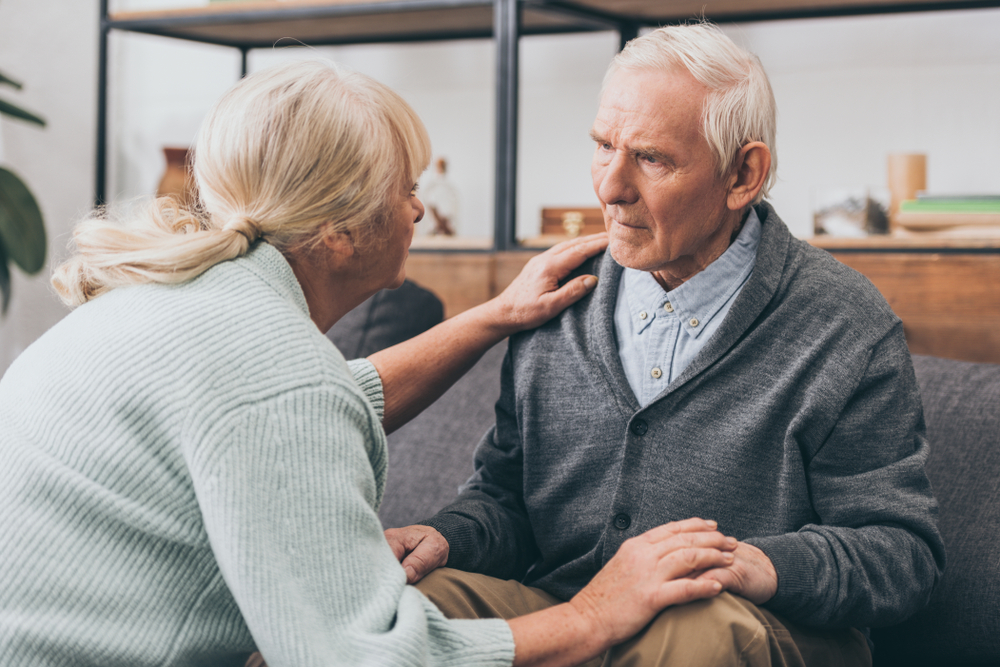 retired couple holding hands and looking at each other at home 