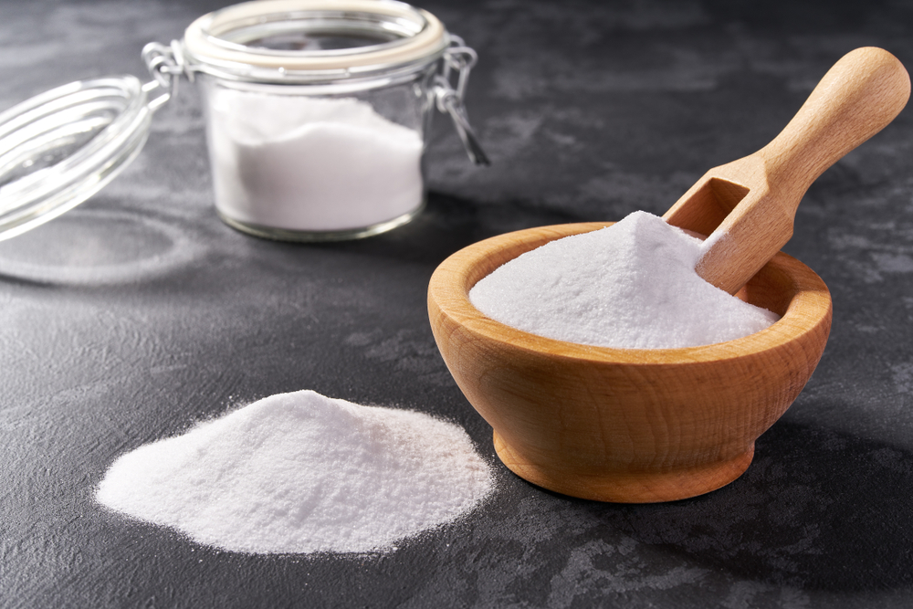 Wooden bowl with sodium bicarbonate on a black background ,copy space
