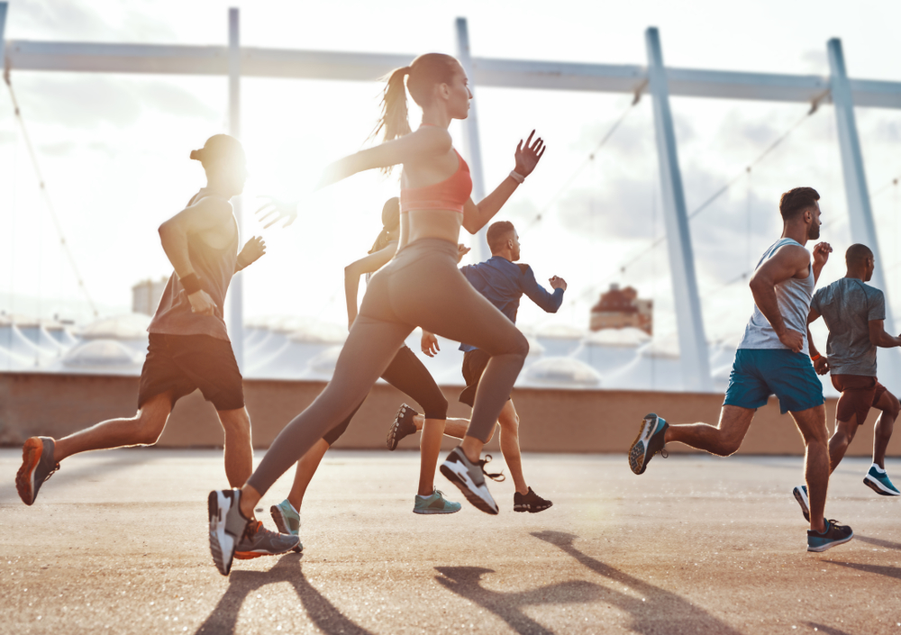 Full length of people in sports clothing jogging while exercising on the sidewalk outdoors