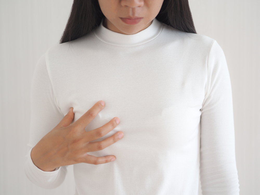breast cancer and breast pain in asian woman and she use hand touching her breast and symptom of change size or shape of one or both breasts use for medicine product or health care concept.