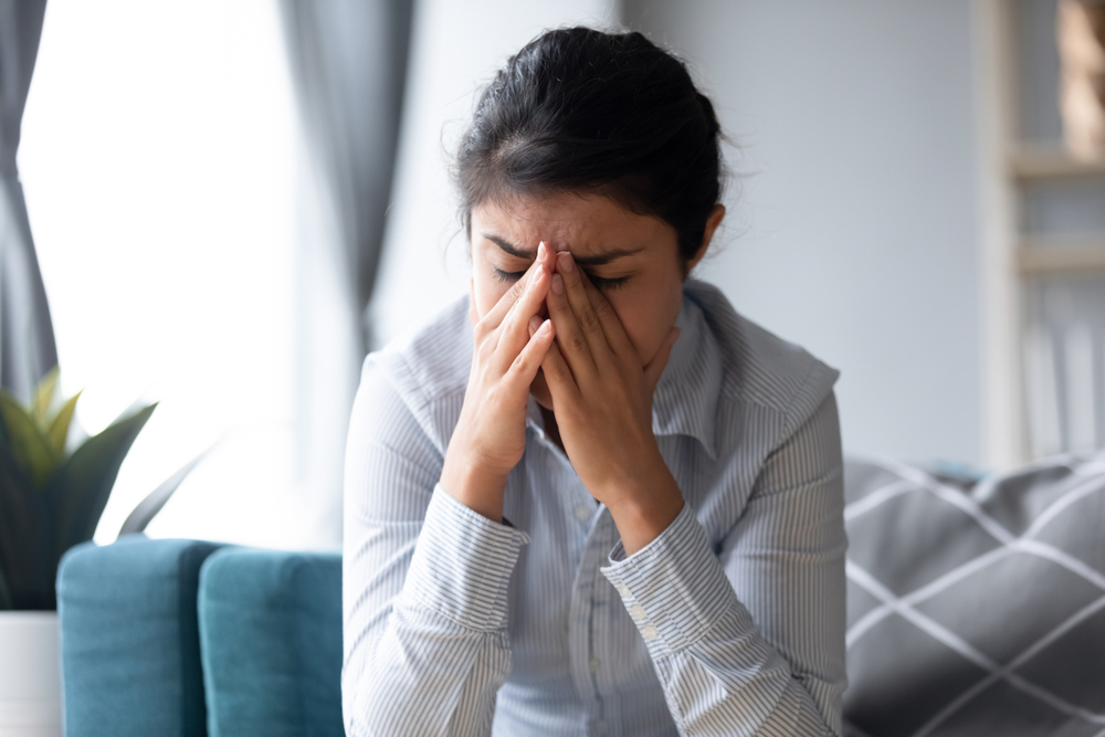 Upset young Indian woman sit on couch feel depressed crying have relationships problems, sad stressed millennial ethnic girl suffer from depression or mental psychological troubles, emotional drama
