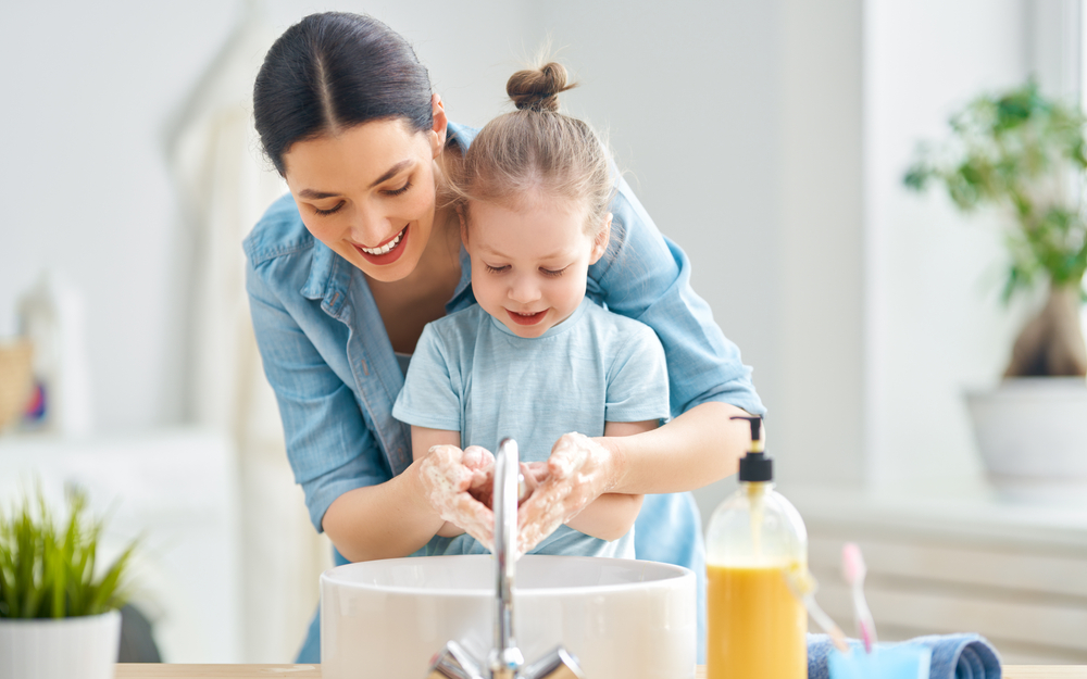 A cute little girl and her mother are washing their hands. Protection against infections and viruses.                               