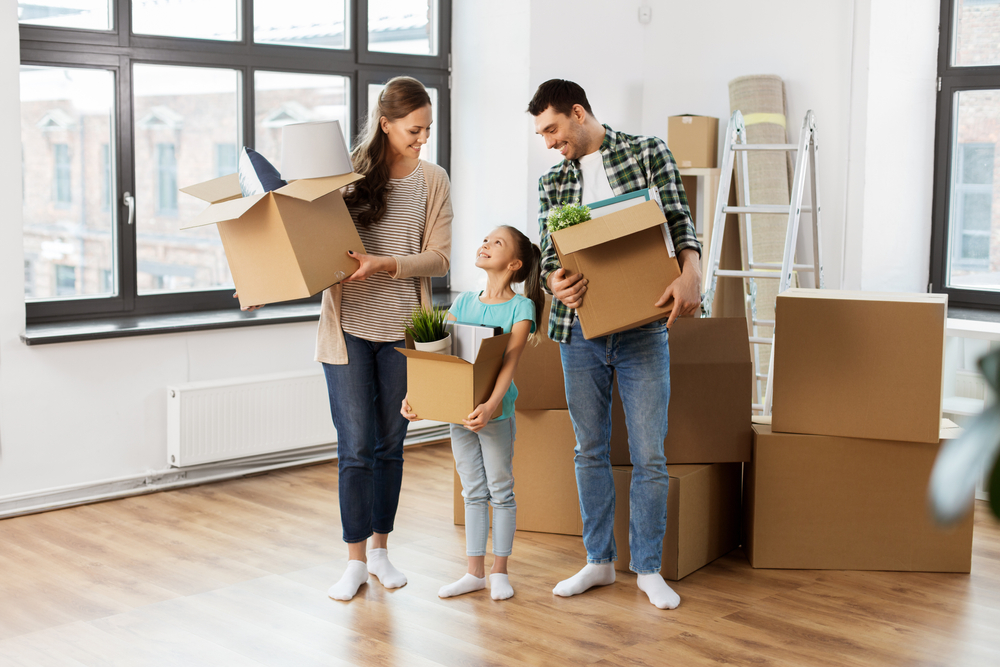 mortgage, family and real estate concept - happy mother, father and little daughter with stuff in boxes moving to new home