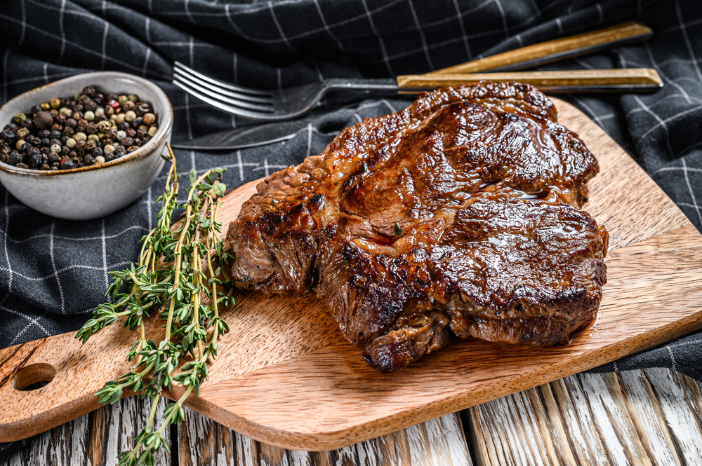 Cooked grilled Chuck eye roll steak on a chopping Board. White background. Top view