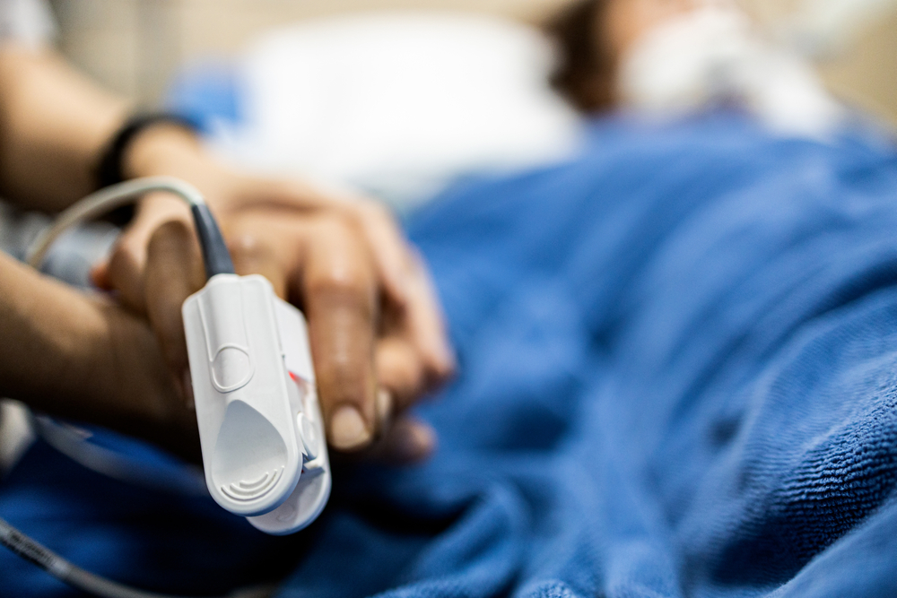 Asian patient's hand with an attached pulse oximeter on finger for monitoring,daughter holding her mother's hand,supporting comforting of seriously ill patient,intensive care in ICU room at hospital