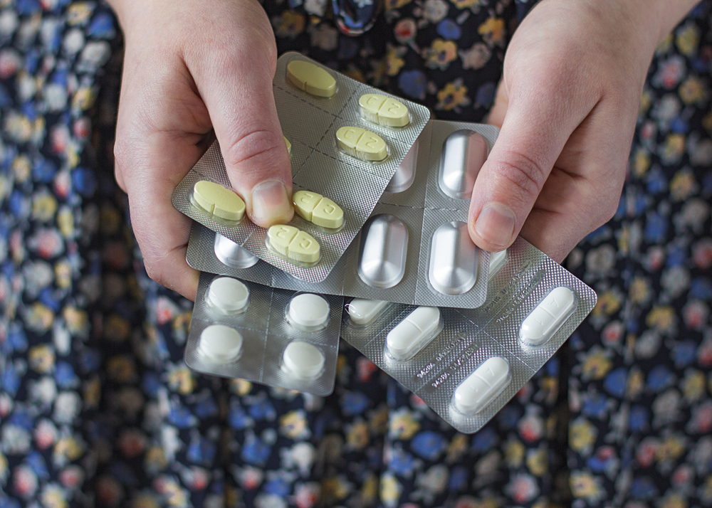 Female hands holding four  kinds of pills in a blister packs. Medicaments on the image a specifically for triple therapy helicobacter pylori treatment: three antibiotics and  proton pump inhibitor.