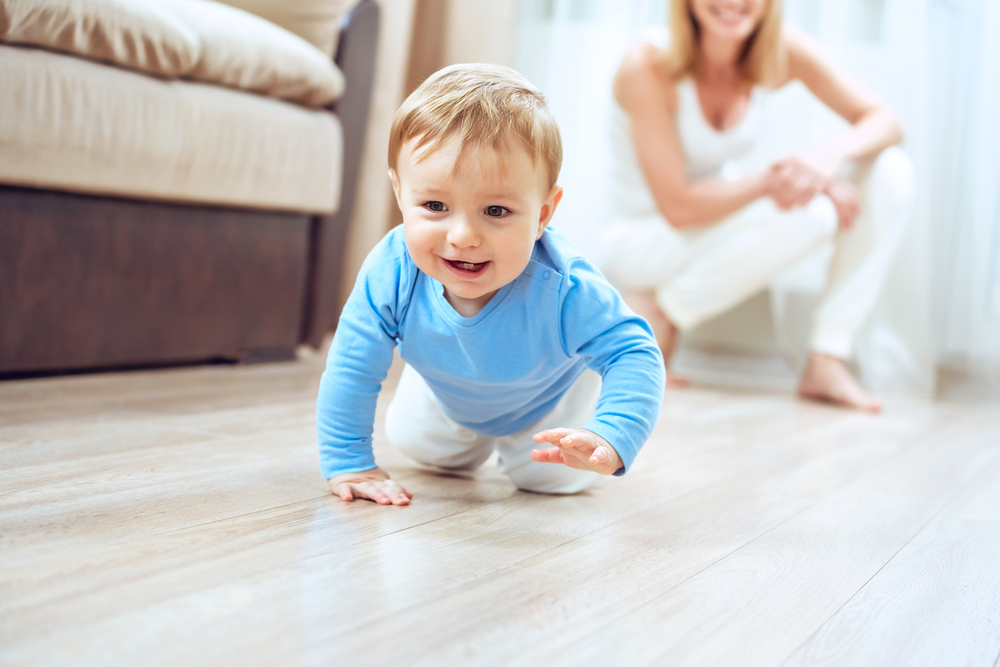 crawling funny baby boy indoors at home. Cute baby and young mother at home