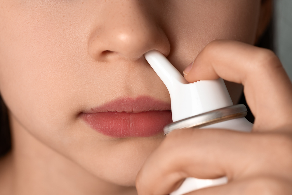 the girl washes her nose with a spray of sea water