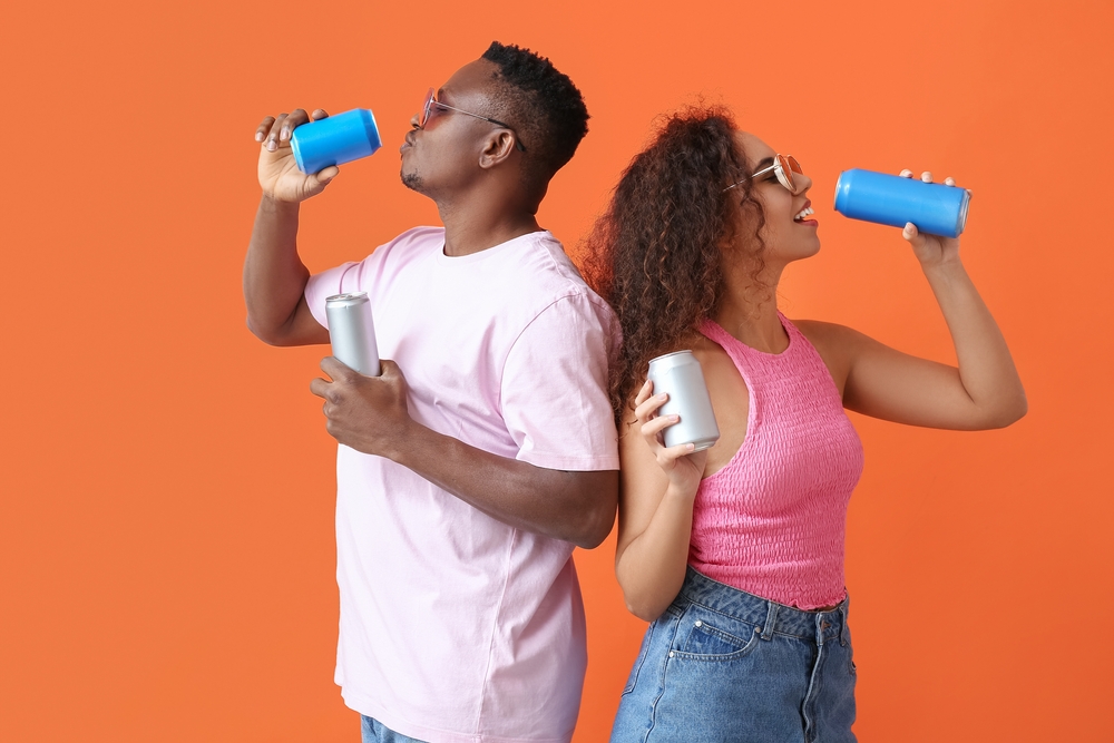 African-American couple with soda on color background
