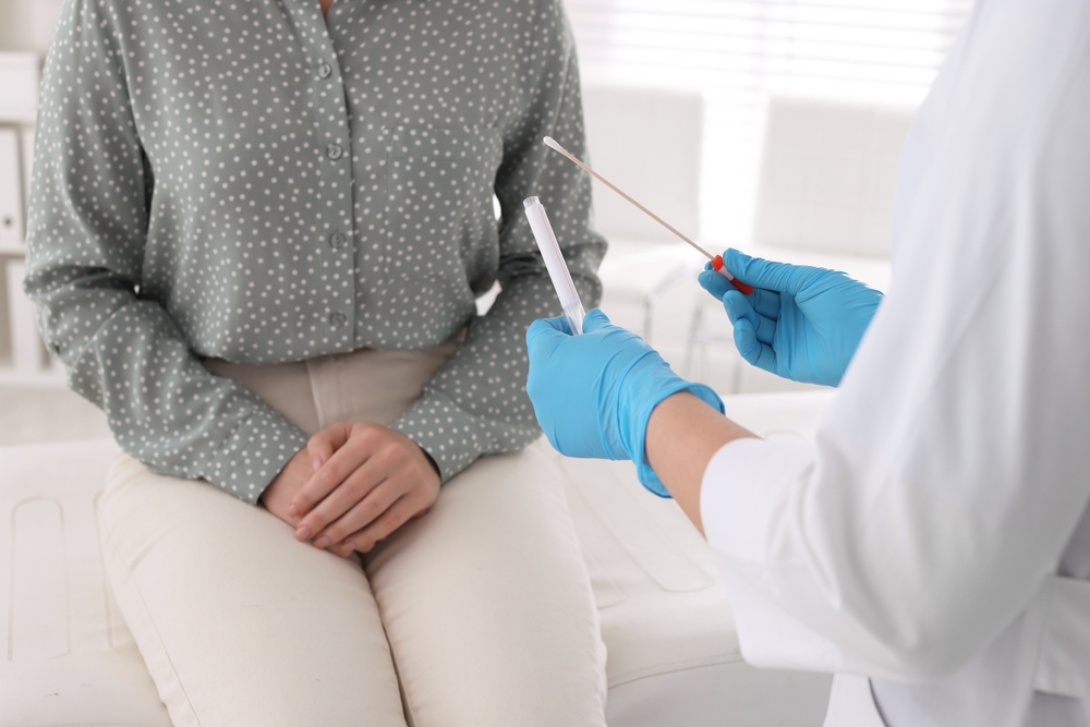 Doctor taking sample for STD testing from woman in clinic, closeup
