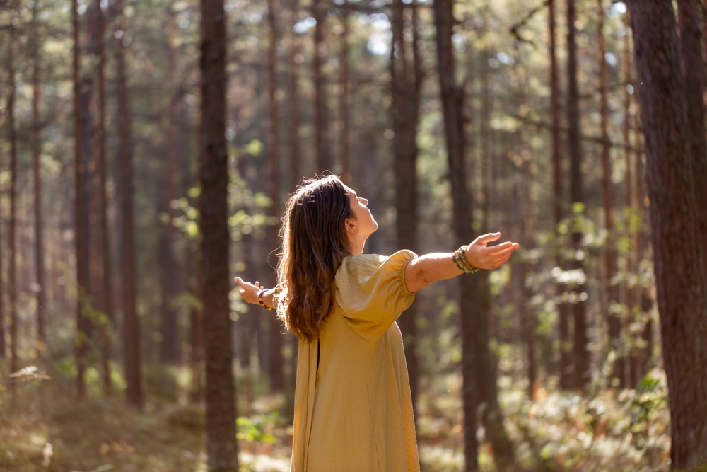 nature, spirituality and supernatural concept - young woman or witch performing magic ritual in forest