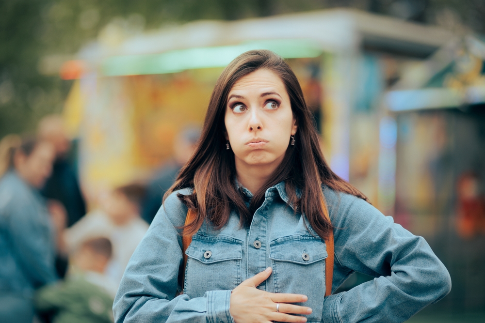 
Woman Feeling Hungry Looking for Something to Eat in Amusement Park. Person accusing stomachaches after eating street food at funfair festival
