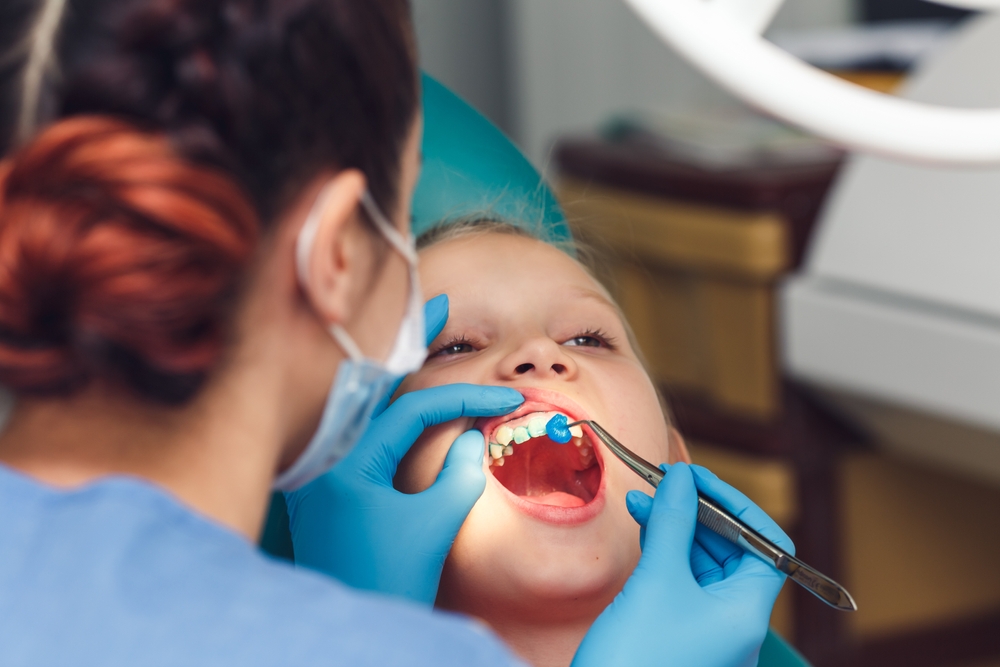 dentist fluoridates a child's teeth. Strengthening of tooth enamel.