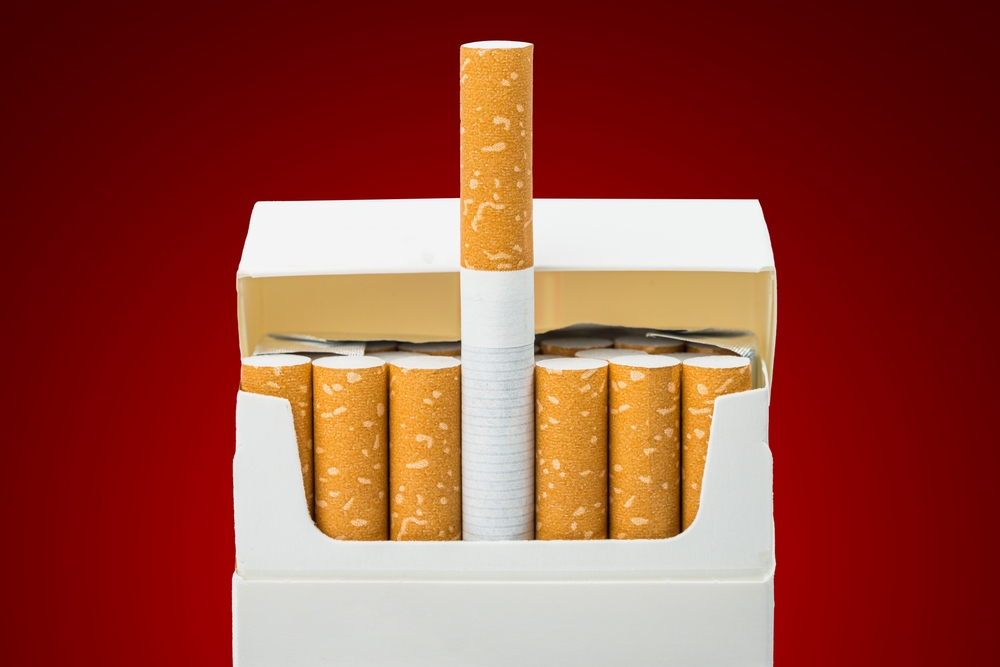 Close up of open pack of cigarettes on red background
