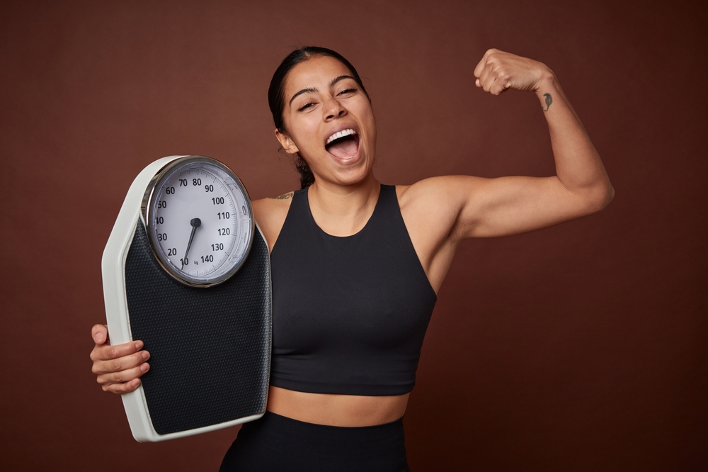 Young fitness woman measuring progress with a scale for healthy living.