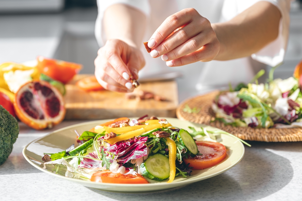 A woman making fresh vegetable salad, close-up, concept of diet and healthy eating.